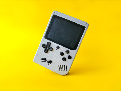 Retro handheld gaming console on a bright yellow background.