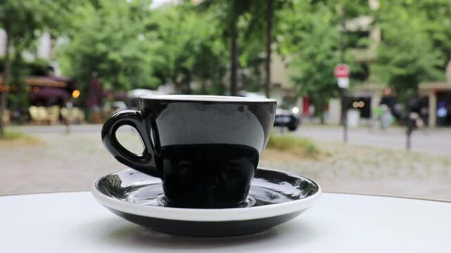 Cup of fresh hot coffee on the table of an outdoor cafe in Paris, France.