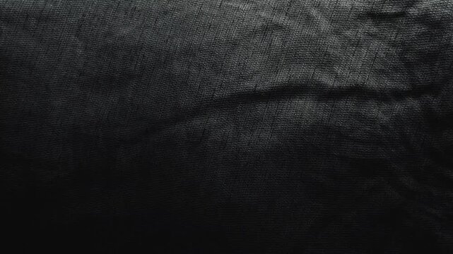 cinematic pan reveals tactile black linen fabric rippling gently creating an abstract moody textile background