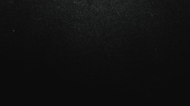 macro texture of black denim fabric slowly moving under dramatic moody studio light
