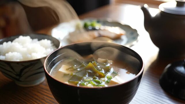 Steaming Bowl of Traditional Miso Soup with Tofu and Seaweed on a Japanese Breakfast Table