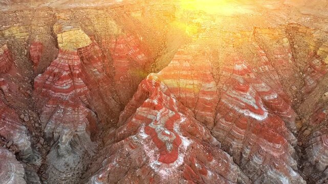 Aerial view of Karynzharyk hollow featuring red and white layered rock formations under bright sunlight in Karakiya District, Mangystau Region, Kazakhstan.