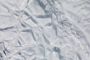 Close-up of cracked and layered ice plates forming an abstract winter texture on Lake Baikal, Irkutsk Oblast, Russia, with bright light and copy space © TravelFlow