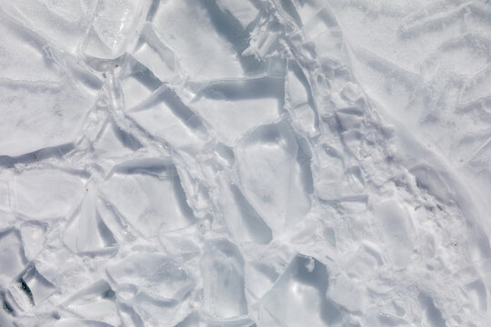 Close-up of cracked and layered ice plates forming an abstract winter texture on Lake Baikal, Irkutsk Oblast, Russia, with bright light and copy space
