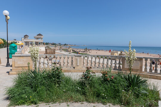 Derbent, Russia - June 18, 2025: Wide view of the Derbent embankment with stone balustrade, flowers and seaside promenade overlooking sandy beach and the Caspian Sea