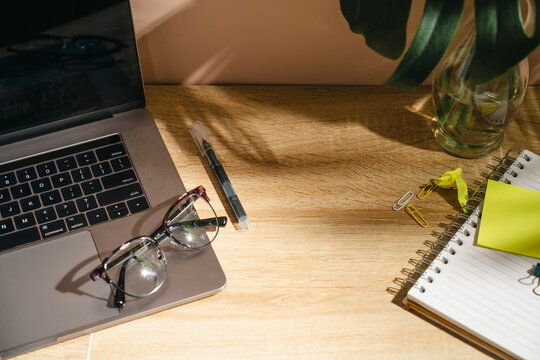 Home office workspace with coffee, laptop and notebook on wooden desk, top view mockup with copy