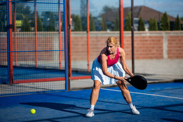 Obraz premium Woman playing padel on a blue court with racket