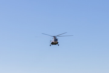 Fototapeta premium Front view of a helicopter flying high against a clear blue sky with wide copy space, ideal for aviation, transport, rescue, security, and travel concepts