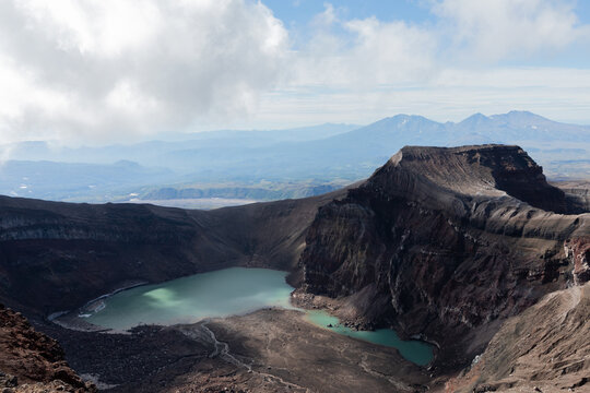 Wide view of Gorely Volcano caldera with turquoise crater lake, ash slopes and rugged ridges under clouds, Kamchatka Peninsula, Russia, remote volcanic wilderness