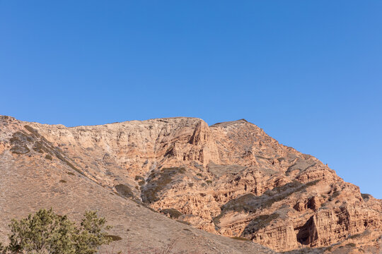 Scenic view of rugged layered sandstone cliffs and dry mountain slopes in Jety-Oguz Gorge, Issyk-Kul Region, Kyrgyzstan, on a clear sunny day with copy space