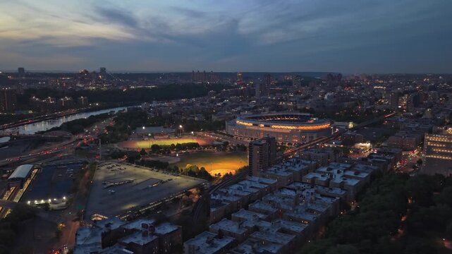 Luminous Yankee Stadium shining in South Bronx, New York City, overlooking Manhattan and Harlem River during evening golden hour