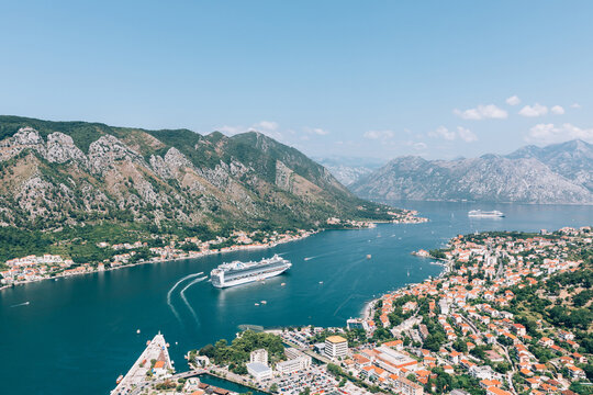High-angle panorama of Kotor and the Bay of Kotor with a cruise ship, marina and red-roof old town, surrounded by steep mountains, Montenegro