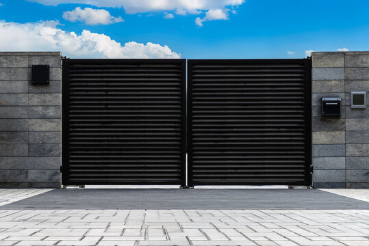 Modern property entrance with closed swing gate, mailbox