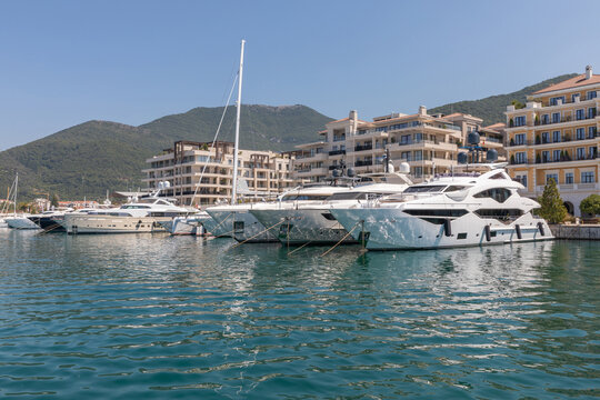 Tivat, Montenegro - August 11, 2025: Luxury yachts and sailboats moored at Porto Montenegro marina with modern waterfront apartments and green mountains in the background, Adriatic Sea