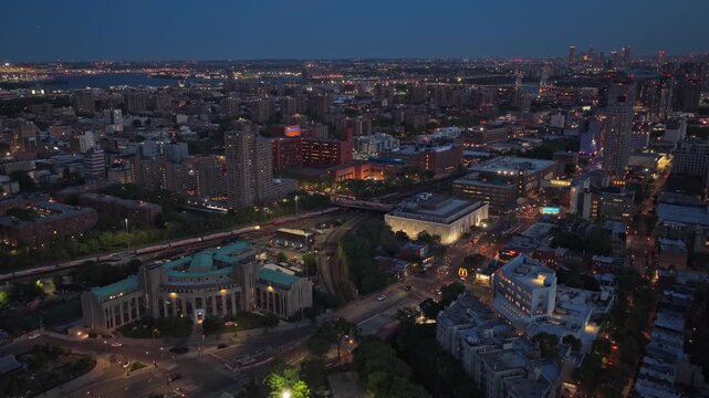 South Bronx urban landscape showing a Metro North train passing near Grand Concourse and Mott Haven, with illuminated buildings during the blue hour