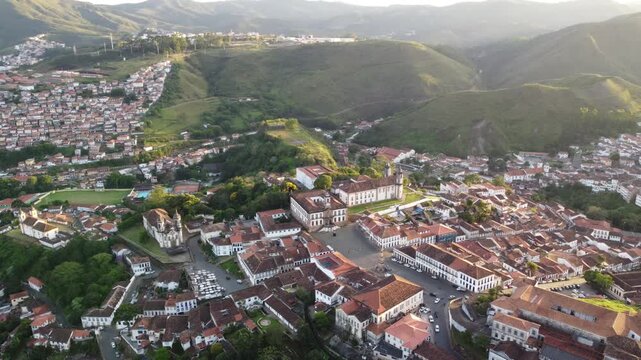 Aerial views of Ouro Preto, Brazil, at sunset, featuring the historic colonial town, iconic churches, rolling mountains, traditional architecture, and the warm light of the golden hour.
