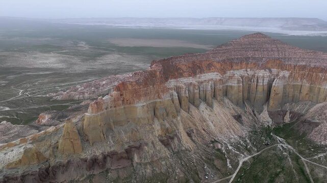 Aerial view of Airakty mountains featuring layered rock formations and vertical cliffs over the arid steppe landscape in Shetpe, Mangystau Region, Kazakhstan.