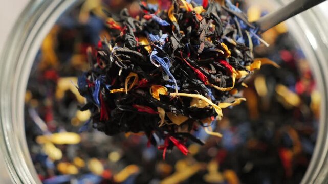Close-up of loose leaf tea with large tea leaves and flower petals. Aromatic herbal blend, natural ingredients and healthy beverage concept. High quality 4k footage