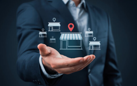 Businessman holding open hand with digital store icons and map pins representing franchise expansion and retail location strategy.