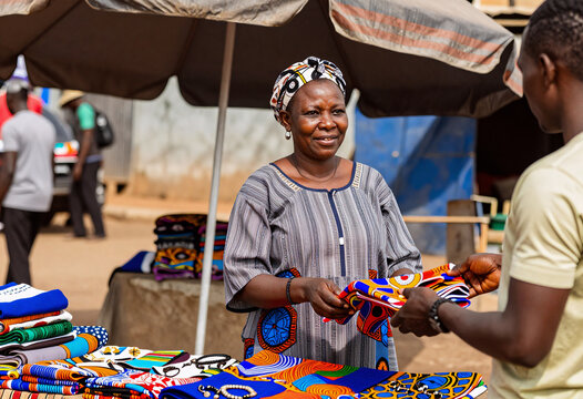 African Woman Selling Colorful Fabrics at Outdoor Market