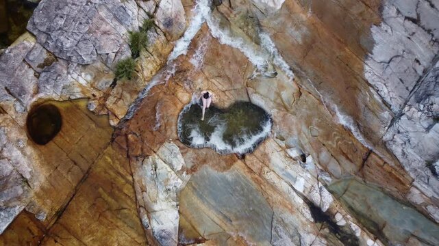 Young woman relaxing in the Heart Pool at Capivara Waterfall, Serra da Canastra, Brazil, surrounded by crystal-clear water, rocky landscapes, pristine nature, and a scenic tropical setting.