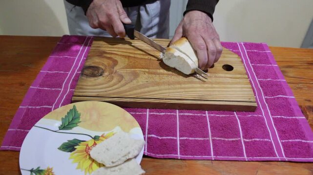 Un hombre cortando rodajas de pan reci&eacute;n horneado sobre una tabla de madera, usando un cuchillo largo de cocina, luz natural suave entrando por la ventana, estilo realista, detalle en textura del pan.