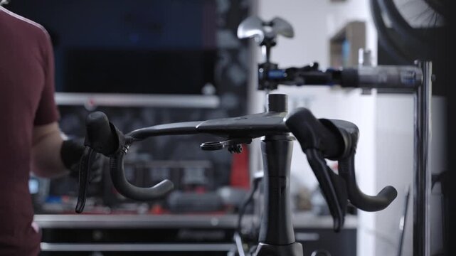 Focused mechanic repairing elite carbon fiber road bike on specialized stand. Bike service station production workflow, professional mechanical skills, technical maintenance of expensive bicycle.