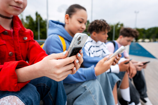 Group of teenagers using smartphones outdoors