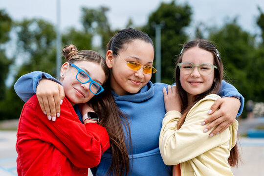 Three teenage girls embracing friendship outdoors in park
