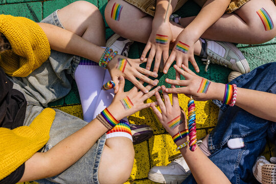 Hands with painted rainbow flags joined in a circle for LGBTQ pride
