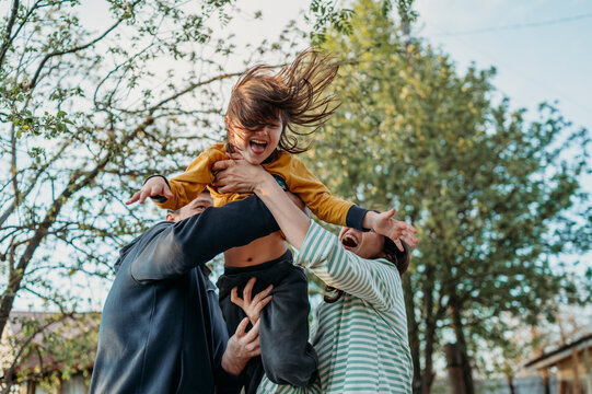 Playful parents lifting son in front yard