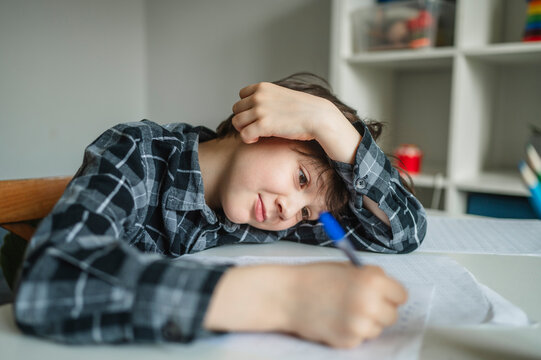 Tired schoolboy studying at home with fatigue and depression