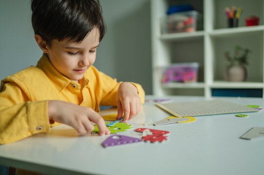 Smiling boy assembling educational toy at table indoors