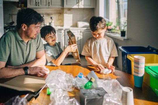 Father and children sorting recyclable waste at home
