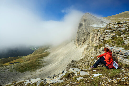 Hiker sitting on a cliff at Col du Charnier enjoying tranquility