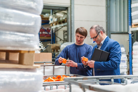 Manager and worker in storage of plastics factory checking products