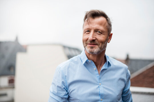 Portrait of smiling mature businessman on roof terrace