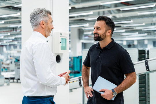 Businessman having discussion with smiling engineer in industry