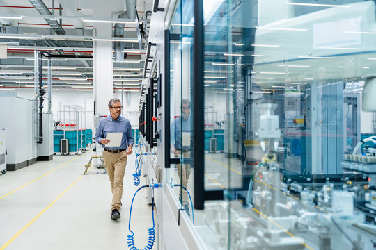 Engineer in modern factory inspecting automation system with tablet
