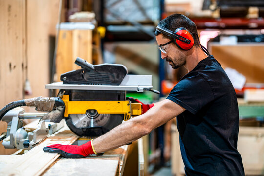 Carpenter cutting wood with electric saw