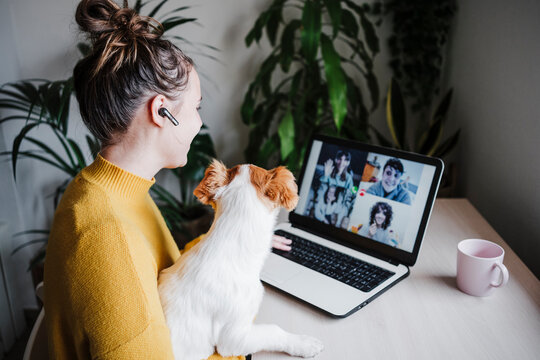 Woman talking with friends on video conference over digital tablet while sitting with pet at home