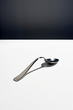 Bent metal spoon on a white surface