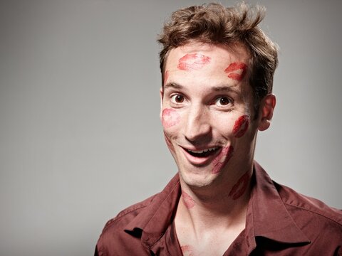 Smiling man covered in red lipstick kisses expressing love and pride