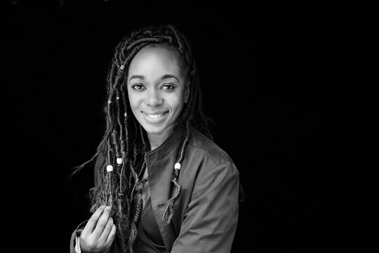 Portrait of smiling woman with dreadlocks in front of black background