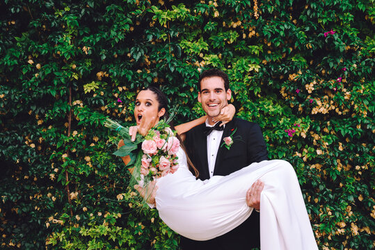 Happy groom holding excited bride in his arms