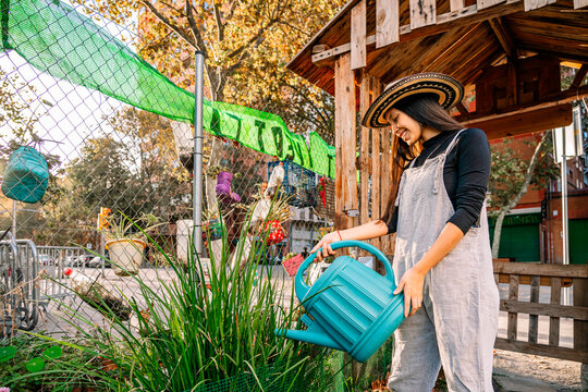 Happy young woman watering plants in garden