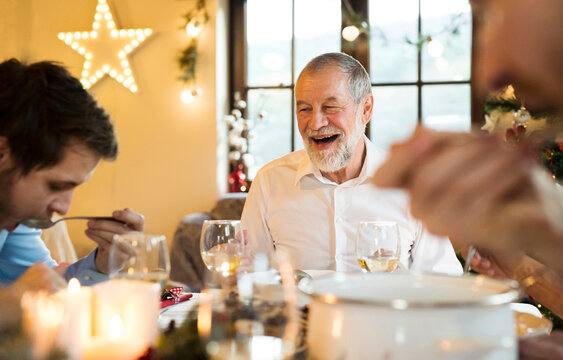 Happy senior man looking at adult son at Christmas dinner table