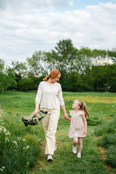 Mother and daughter holding hands while walking in a green meadow