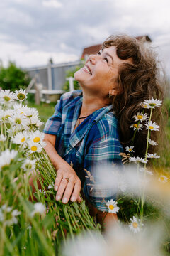 Smiling woman looking up among daisies in a summer garden