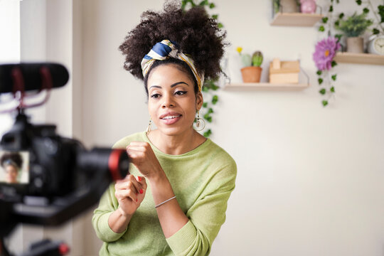 Young woman wearing headband filming through camera at home